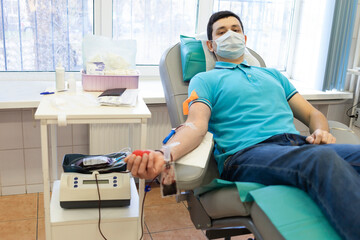 bone marrow donation. man in medical mask, male hand holding red ball, blood transfusion system, blood bag. soft focus - obrazy, fototapety, plakaty