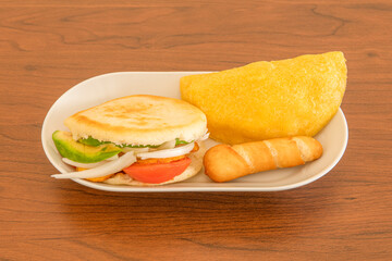 Small tray with Venezuelan appetizers, arepa with tomato, banana onion and avocado, tequeño stuffed with fresh cheese and cornmeal empanada