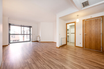 Empty apartment with kitchen, large window, aluminum radiators and chestnut wood parquet floors