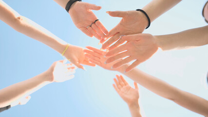 Cheerful girls join hands together as a sign of unity and joint successful work. Teamwork stacking hand concept.