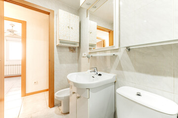 Bathroom with mirror and toilet with white furniture and lots of light in a holiday rental apartment