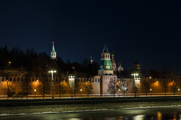 Moscow, Russia.  Night view of The Kremlin:  towers, wall, trees behind the wall. St. Basil's cathedral in background