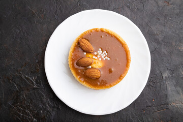 Sweet tartlets with almonds and caramel cream on a black concrete background. flat lay.