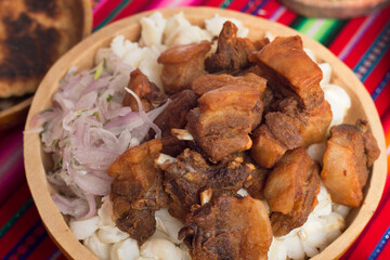 comida peruana, plato de chicharrones de chancho con mote y ensalada de cebolla