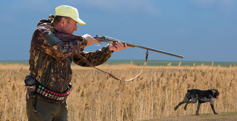 Hunter man in camouflage with a gun during the hunt in search of wild birds or game. Autumn hunting...