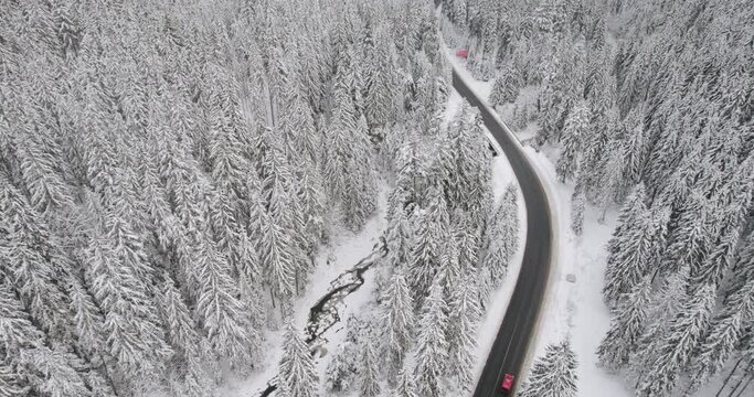 Aerial top down cinematic winter snow cowered country road, asphalt serpentine. Cinematic suburban landscape.