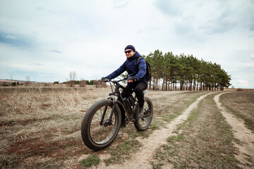 A man rides a fat bike on the road. Rural area.
