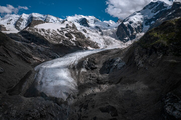 Morteratsch Glacier with snowy mountains in the Engadin in the Swiss Alps in summer with blue sky and sun.