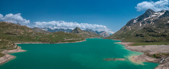 Fototapeta na wymiar Mountain panorama at the reservoir lake Lago Bianco at the Bernina Pass with blue sky and sun from above in summer.