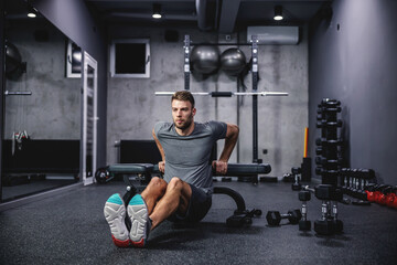 Fototapeta na wymiar A male athlete does triceps push-ups on a sports bench workout in a modern gym. The concept of fitness training, sports, pumping arm muscles, press ups