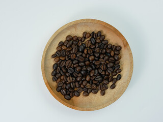 quality coffee beans on wooden plate isolated on white background.