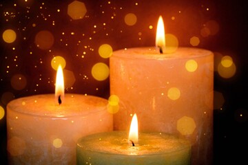 Burning candles with festive bokeh on a black background. Holiday concept.