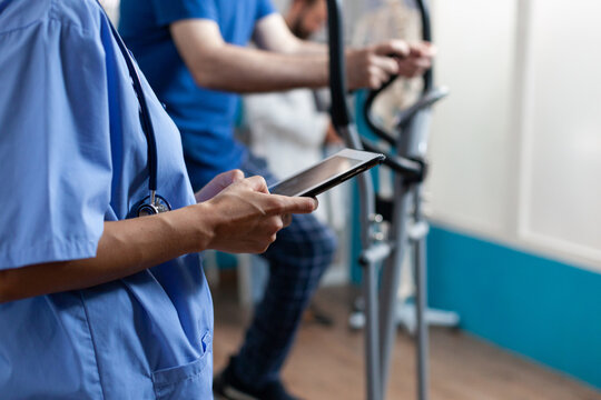 Close up of nurse holding digital tablet with touch screen at recovery clinic. Medical assistant using modern device for healthcare and physiotherapy to heal injury for senior people
