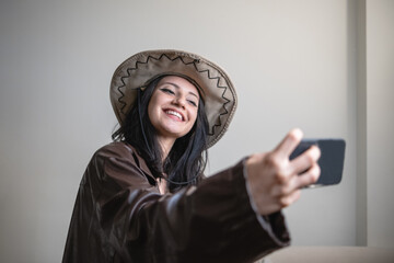 young fun woman in cowboy hat and leather jacket taking selfie