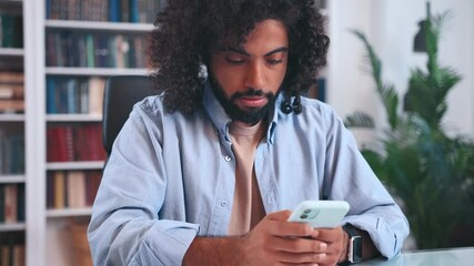 Young Arabian man student gets nervous typing message or passing exam on phone sends application to college and experiences stress sits at table in office. Education, study, university enrollment