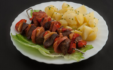 Meat skewer with potatoes on a white dish