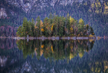Forrest island on a lake with a reflection in autumn