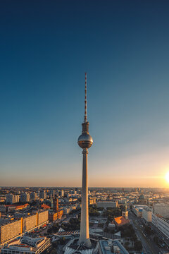 Vertical shot of the tv tower in berlin rising above all buildings with a sunset background