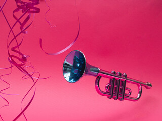 Pink and blue metallic trumpet and party decorations on pink background. New year party concept. 
