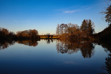 Fototapeta na wymiar Still und starr ruht der See, - traumhafte Landschaft mit spiegelndem See unter blauem Himmel.
