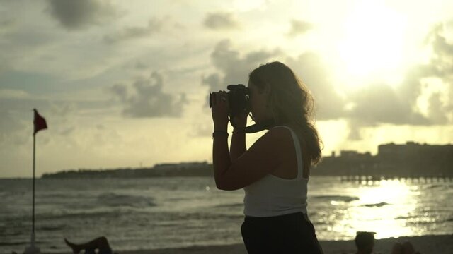 beautiful female photographer taking pictures of model. Beach summer sunset. High quality FullHD footage