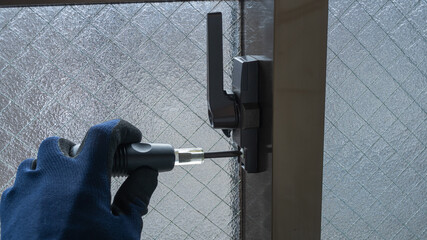 サッシ窓の錠を調整・交換する作業員