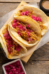 Pork meat tacos called cochinita pibil on a wooden background. Mexican food