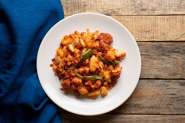 Potatoes with chorizo on a wooden background.  Mexican food