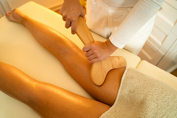 Madero therapy leg massage, closeup shot of masseuse with wooden object for massage in her hands
