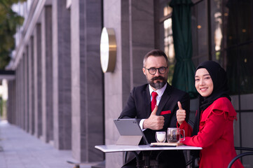 Businessman caucasian and business woman Muslim discussing, consulting, exchanging ideas, analyzing, considering, reasoning about work.