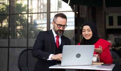 Businessman caucasian and business woman Muslim discussing, consulting, exchanging ideas, analyzing, considering, reasoning about work.