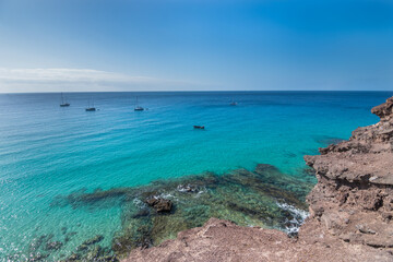 Obraz premium View of the beautiful and colorful Morro Jable Beach (Playa Morro Jable) from a viewpoint close by - Fuerteventura, Canary Islands, Spain