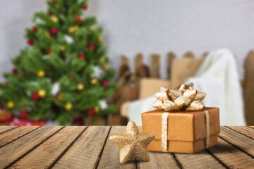 Wooden tabletop with gift Christmas decoration and blurred modern room as background.