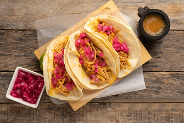Pork meat tacos called cochinita pibil on a wooden background. Mexican food