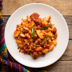 Potatoes with chorizo on a wooden background.  Mexican food