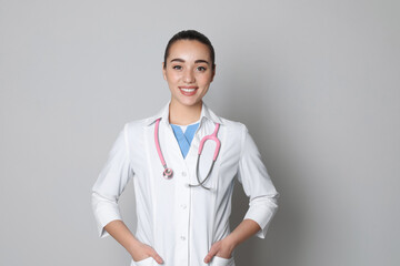 Portrait of beautiful young doctor on light grey background