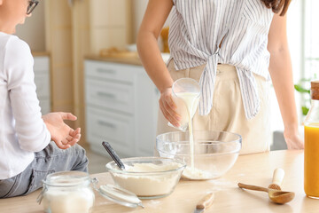 Obraz na płótnie Canvas Teenage girl and her little brother preparing dough in kitchen