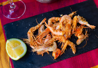 Crispy battered shrimps served with lime on black plate - obrazy, fototapety, plakaty