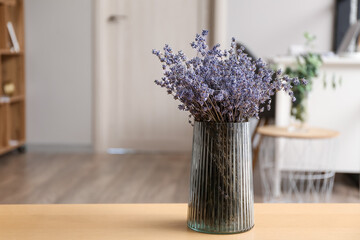 Vase with beautiful lavender flowers on table in room