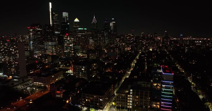 Aerial establishing shot of downtown urban city skyscrapers at night. Dramatic beautiful lights against dark sky.