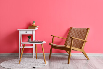 Wooden armchair with table near pink wall