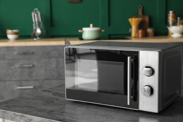 Modern microwave oven on table in kitchen - obrazy, fototapety, plakaty