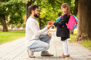 Man giving his little daughter an apple before school