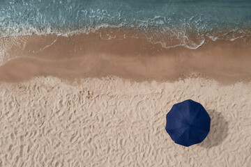 Obraz premium Beach umbrella on sandy coast near sea, top view
