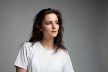 attractive female model four thirds view in blank white t-shirt and jeans isolated on gray background