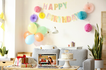 Laptop, gifts and cake on table in room. Celebrating birthday online due to coronavirus epidemic