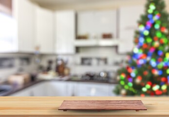 Wooden tabletop with cutting board and blurred kitchen with Christmas tree. Background for display or montage your products.