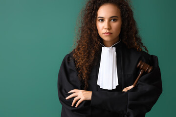 Young female judge with gavel on color background