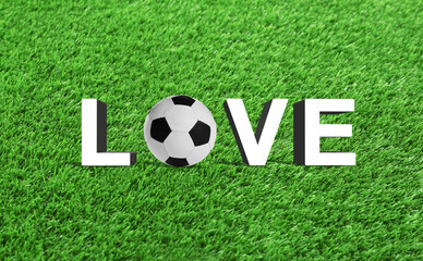 Word LOVE made of letters and soccer ball on green grass