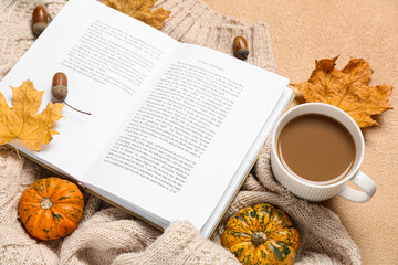 Fototapeta na wymiar Cup of tasty coffee, book and autumn decor on beige background